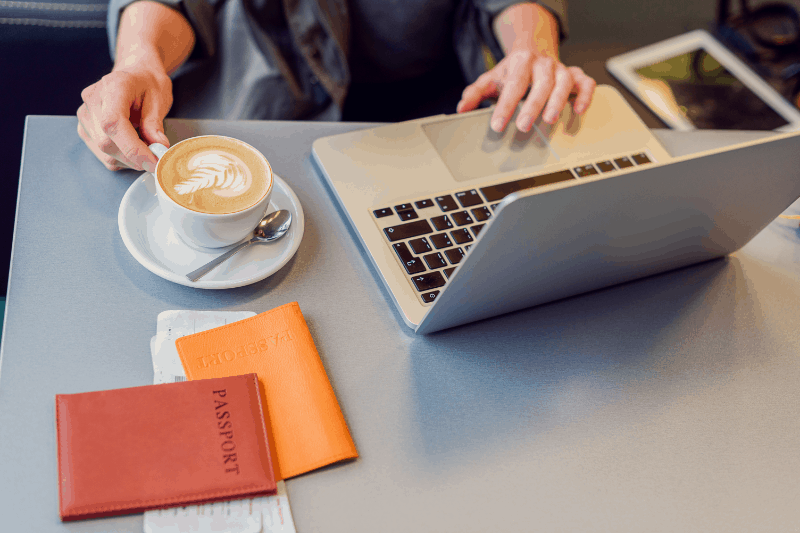 book international flights with a cup of coffee, a laptop and passport information