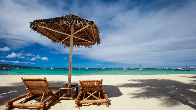 two beach chairs with umbrella on white sand beach at a Boracay resort