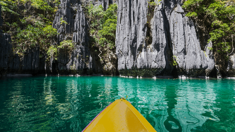 Front point of yellow kayak in small lagoon on Palawan. Karst tock formation in the background