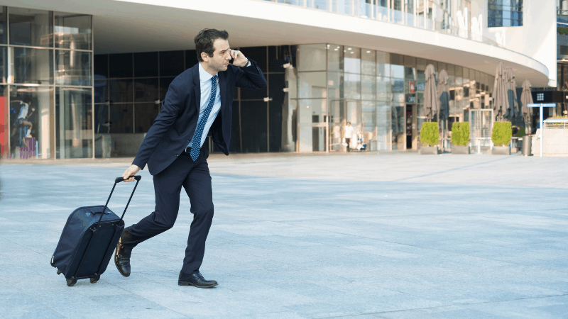 Man on phone with suitcase rushing to the airport