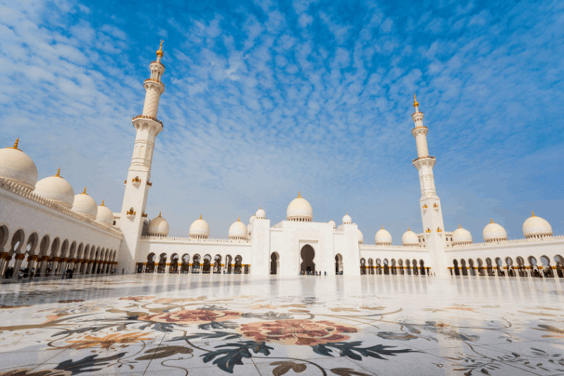 courtyard and white buildings of sheikh zayed grand mosque abu dhabi - essential for a uae itinerary