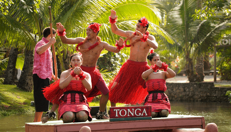 Five people performing at the polynesian cultural center, a top Oahu attraction. Sign on the stage says Tonga