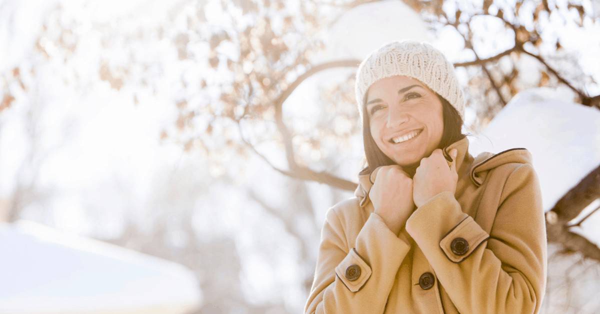 woman bundled up for winter getaways in new england - blurred snowy background