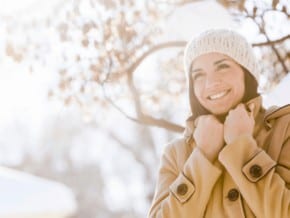 woman bundled up for winter getaways in new england - blurred snowy background