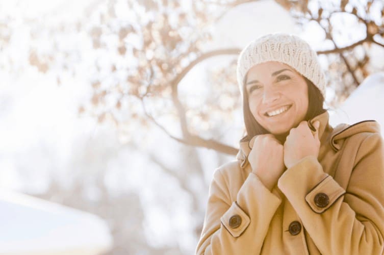 woman bundled up for winter getaways in new england - blurred snowy background