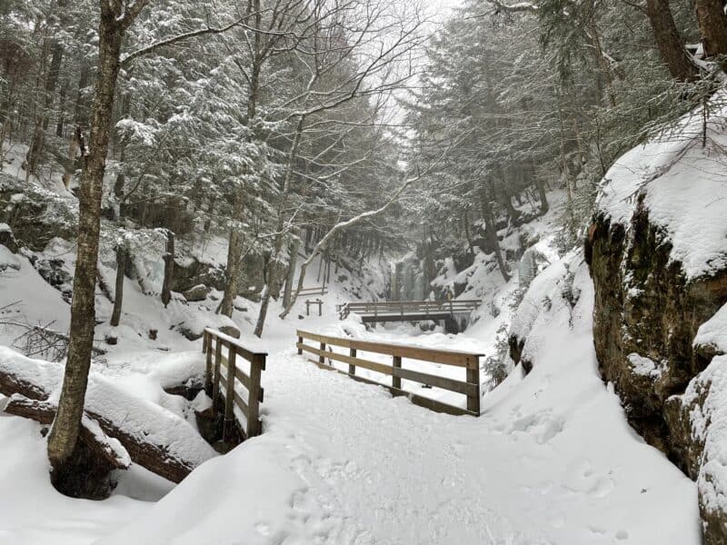 A snow covered path with wooden bridges, for a winter vacation in New England, This is where to go for the best winter vacations in US. 