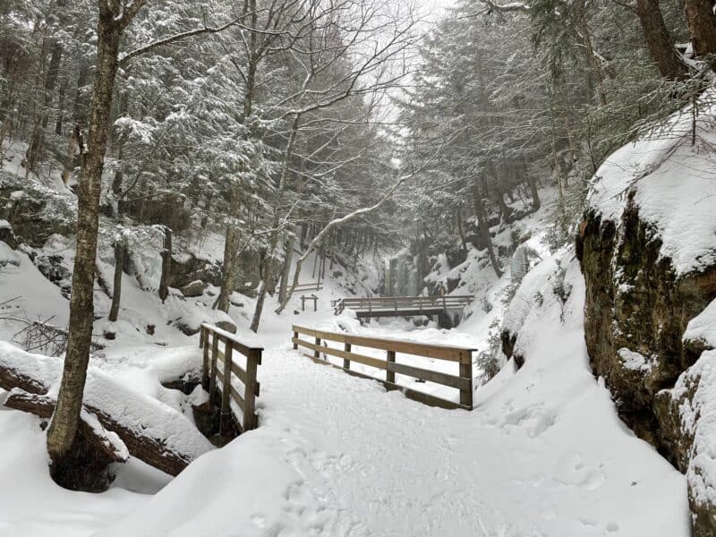 A snow covered path with wooden bridges, for a winter vacation in New England, This is where to go for the best winter vacations in US.