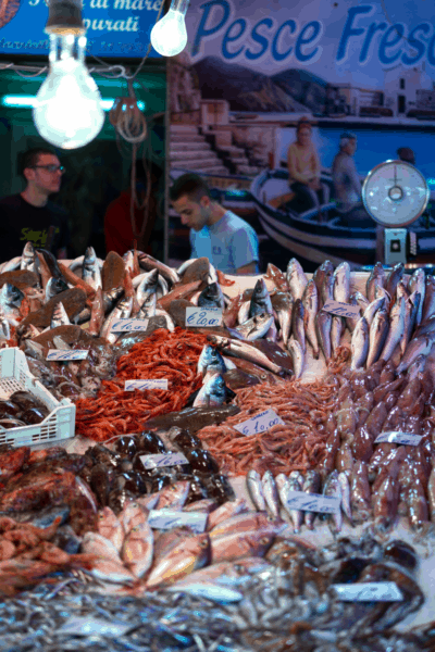 fish vendor in Sicily with prawns and other shellfish in foreground