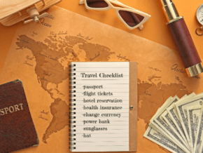 Assorted travel related items surrounding a notebook with a checklist of things to prepare before travelling abroad