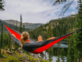The art of slow traveling: A woman in a hammock looking out over a canopy of trees. 