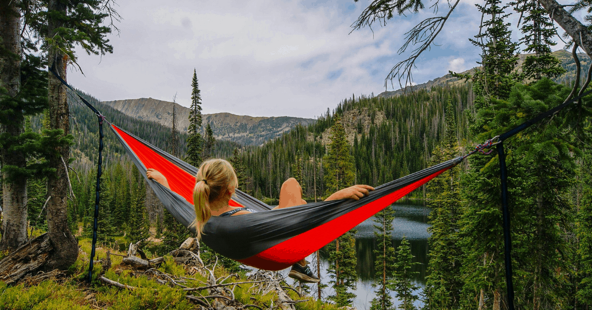 The art of slow traveling: A woman in a hammock looking out over a canopy of trees. 