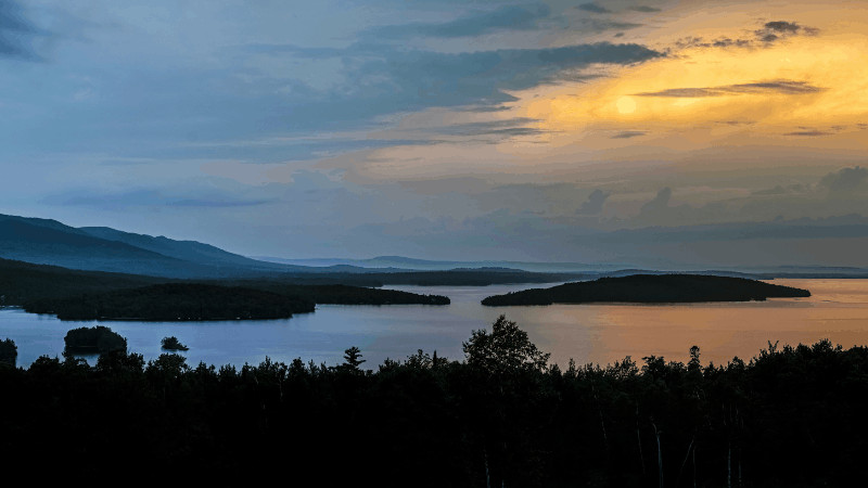 sun shining through clouds above moosehead lake maine
