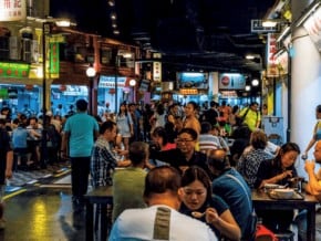 People eating at one of the hawker centres in Singapore. Hawker stalls in the background