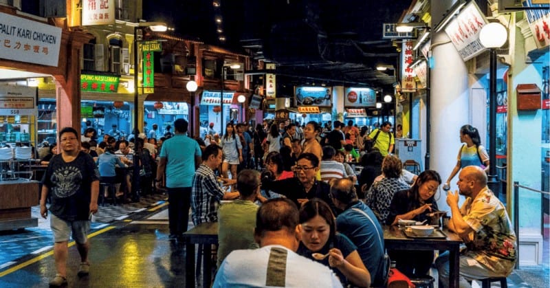 People eating at one of the hawker centres in Singapore. Hawker stalls in the background
