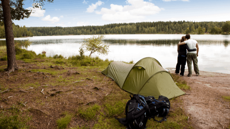 couple embracing in front of a tent on a lake