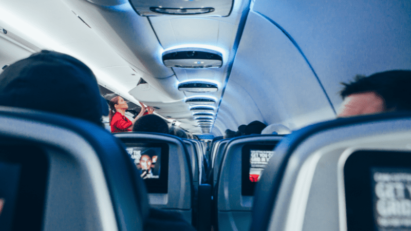 view down the aisle of a plane while people are using airplane console seatback entertainment