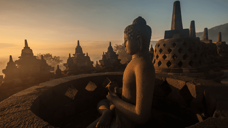 Buddha statue and stupas at Borobudur. Sunrise in background