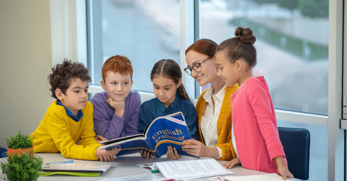 Woman teaching English to children standing around her