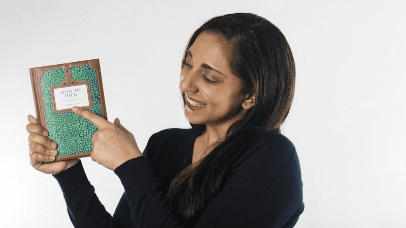 woman pointing to the How to Pack book
