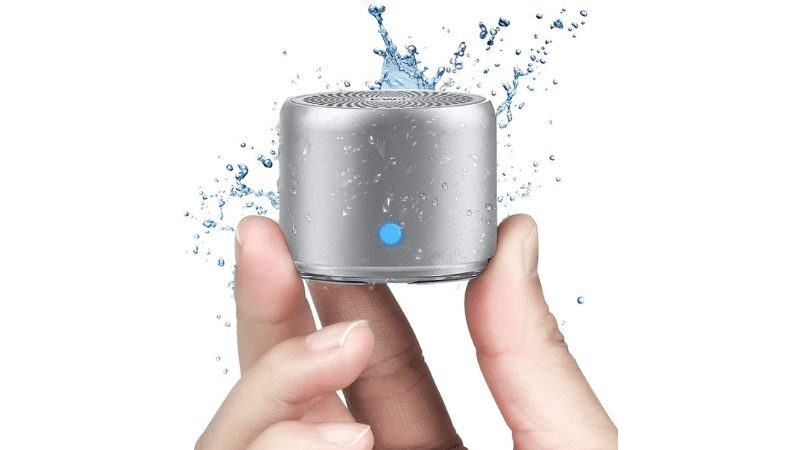 Fingers holding a waterproof mini speaker