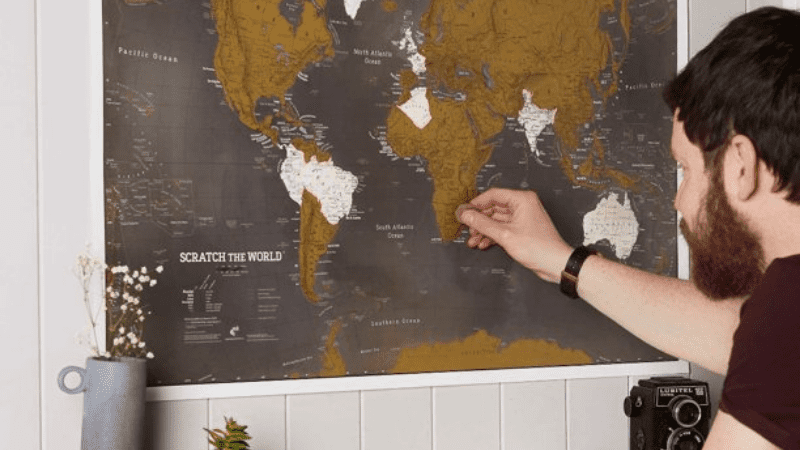 man scratching off a country on the scratch the world travel map