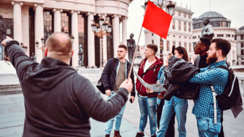 tour guide holding a flag and talking to a group of tourists