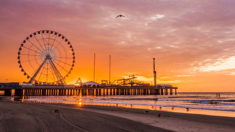 Atlantic City beach and pier with amusement park. Silhouetted by sunset over the water.