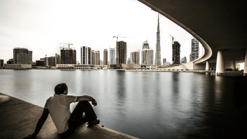 Man in UAE sitting on the ground looking at the Burj Khalifa in the sitance