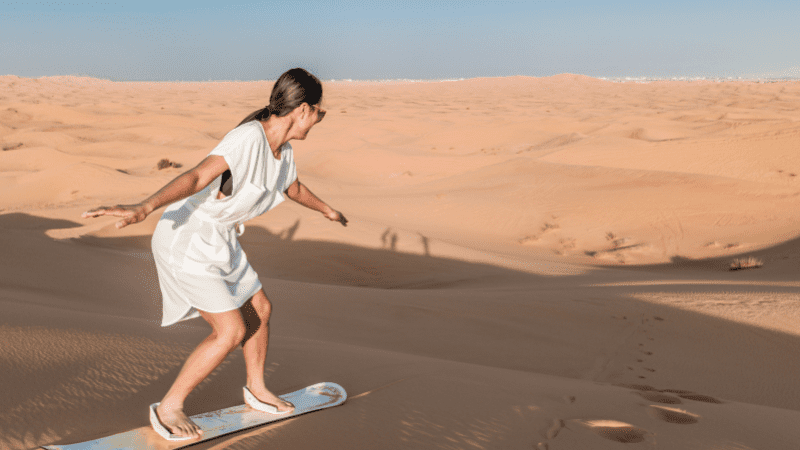 person sandboarding on a desert safari in UAE