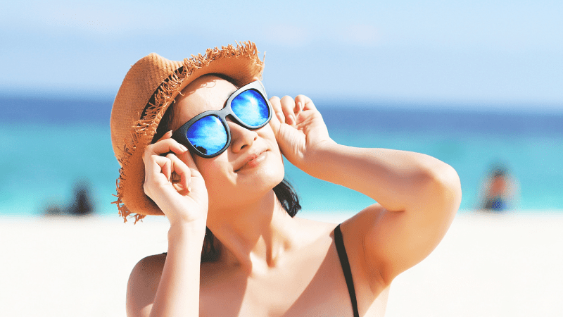 woman wearing a hat and sunglasses on the beach