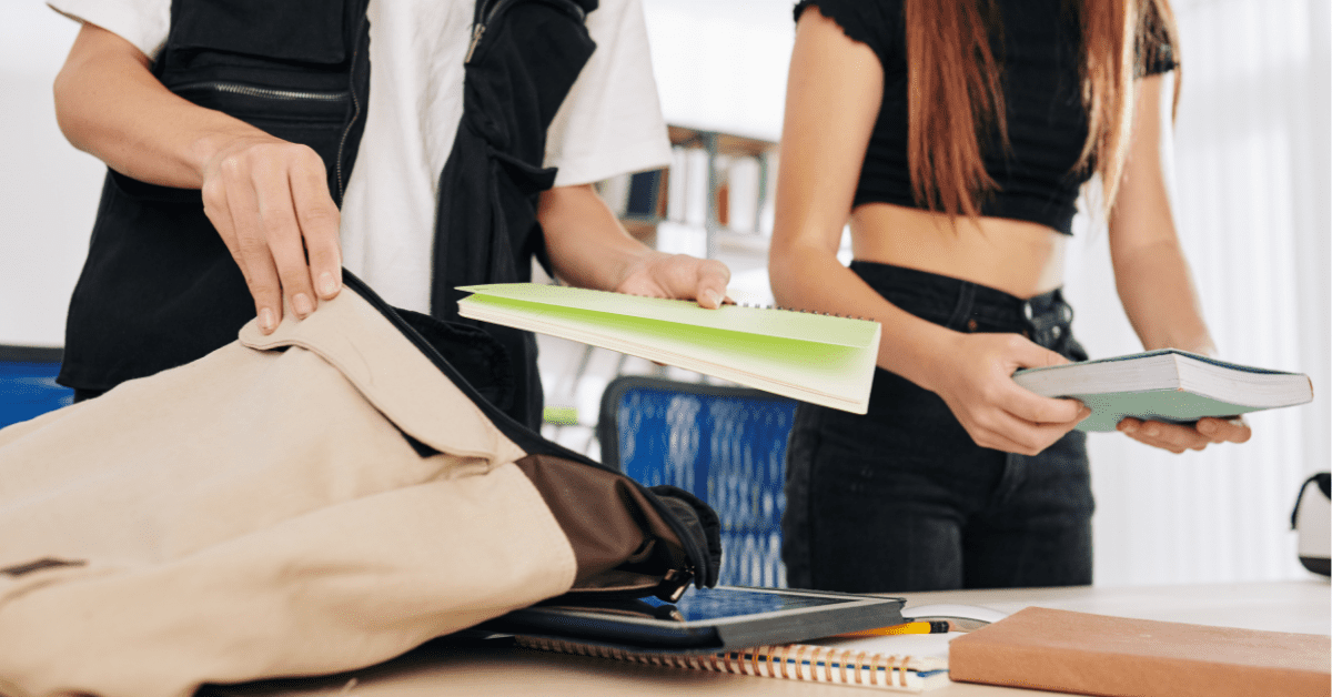 Couple holding books and a carry on bag