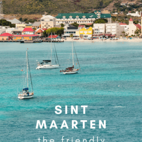 boats at anchor with small town and hill in background.. Text overlay says sint maarten the friendly island