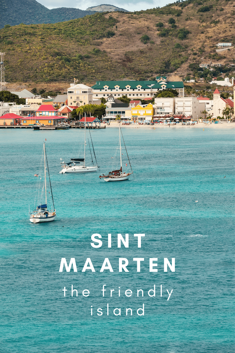 Sailboats at anchor at St. Maarten island, with small town and hill in background.. Text overlay says "sint maarten the friendly island." st martin island, saint martin island, things to do in st maarten, st martin caribbean, st martin island caribbean. st martin virgin islands, mullet bay, pinel island, st-martin, st. martin island, st. martens