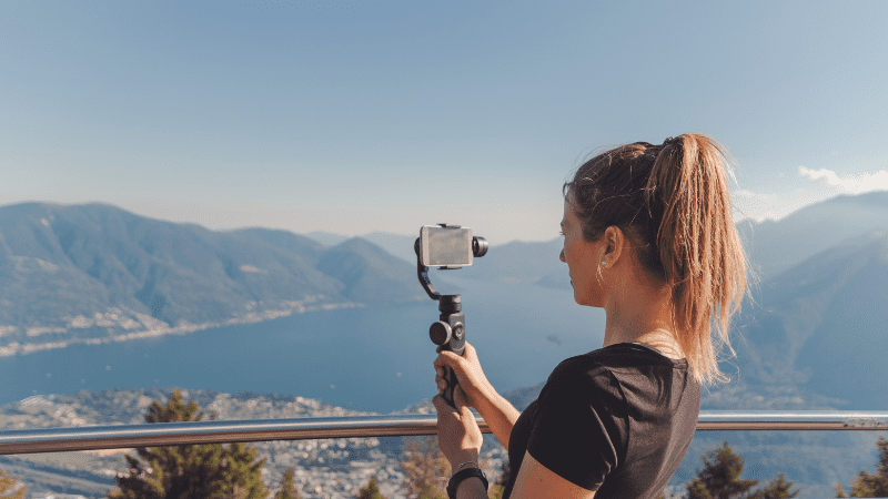 woman with camera taking video of lake in background
