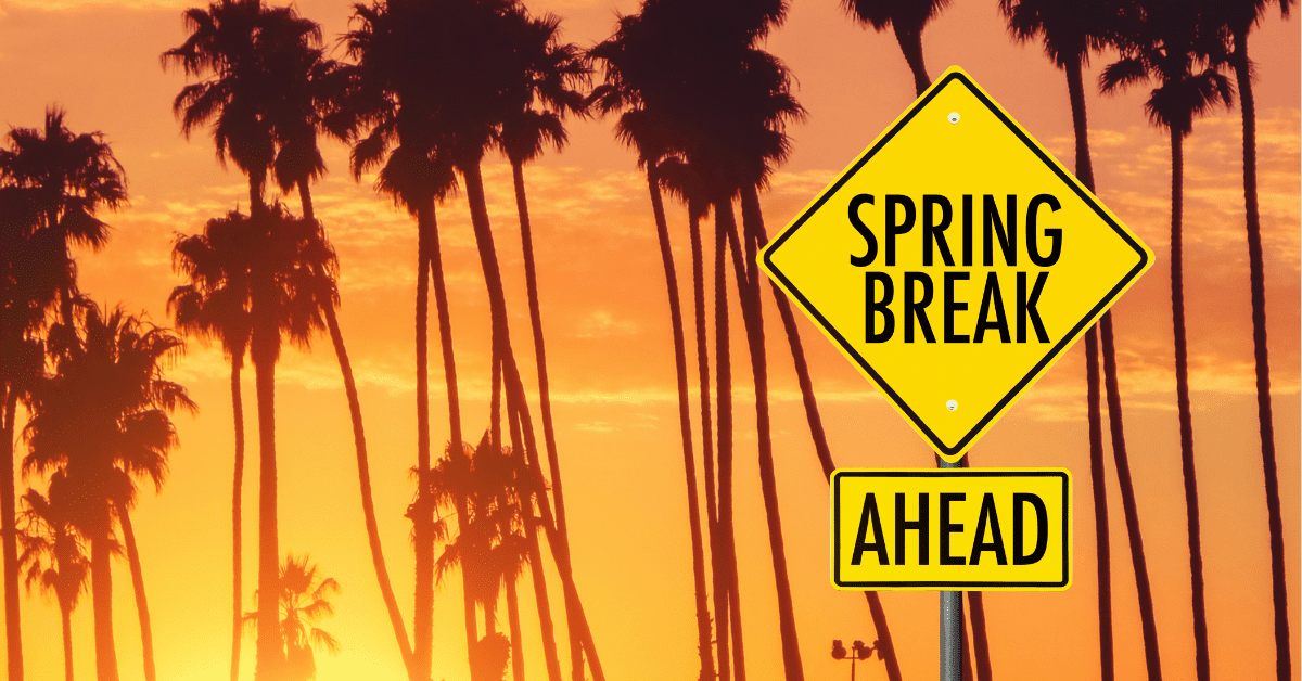 palm trees silhouetted against an orange sunset sky. Sign says spring break ahead. 