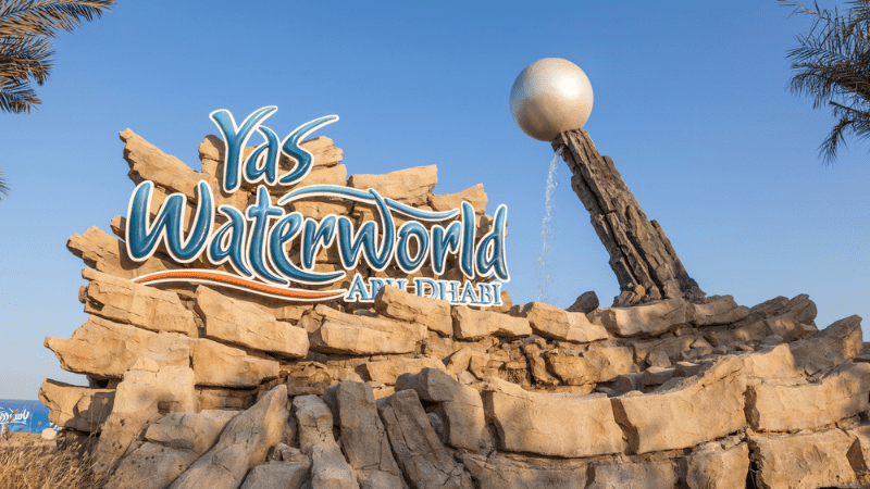 Sign for Yas Waterworld Abu Dhabi with rides in background