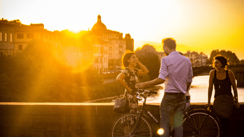 Sunset flare on lens, with People on the Ponte Vecchio. This bridge is one of the most romantic places in Florence Italy.