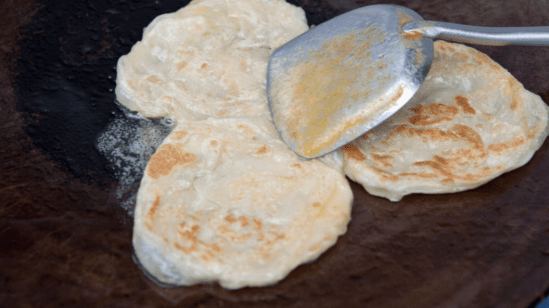 wok with scoop preparing thai banana roti