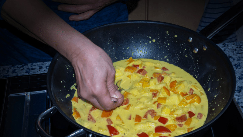 Woman's hand scooping up Massaman Thai curry