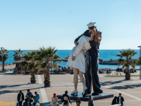 People standing around a statue of a sailor kissing a nurse on Civitavecchia's waterfront.