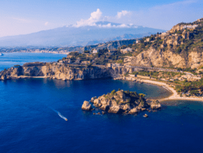 blue waters surround a town and beach in sicily