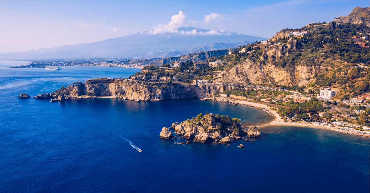 blue waters surround a town and beach in sicily