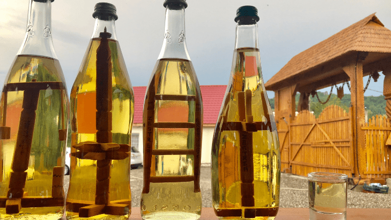four bottles of palinka on a table with a Hungarian building in the background