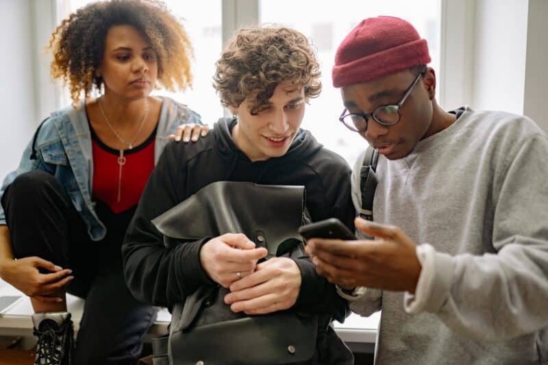 Three college students looking at a cell phone