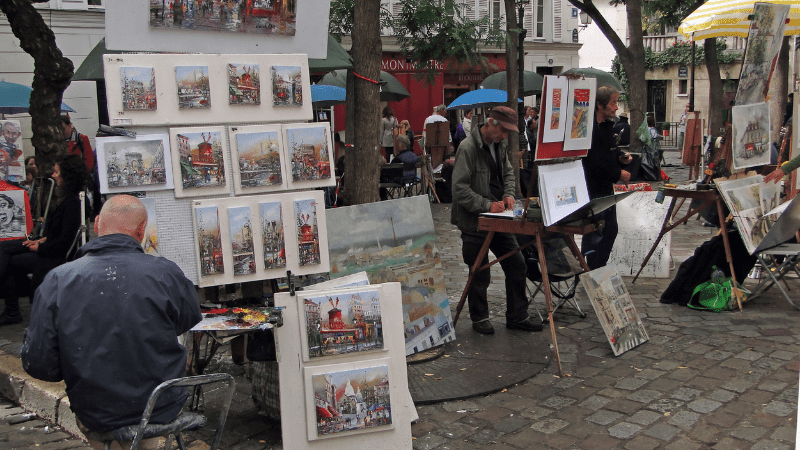 Artists on the streets of Paris, next to displays of their artwork.