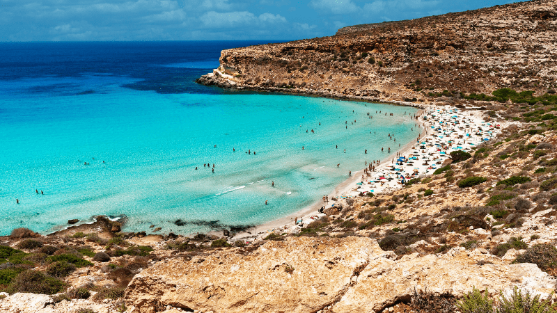 People on the sand at Spiaggi dei Conigli Beach in Sicily
