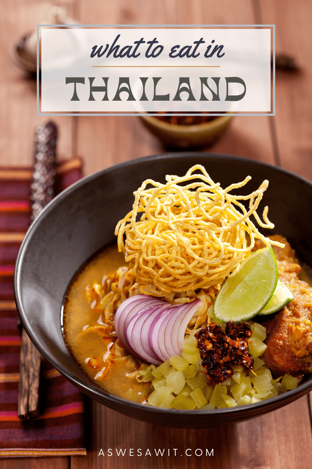 bowl of khao soi soup topped with a pile of crunchy noodles. Text overlay says "what to eat in Thailand"