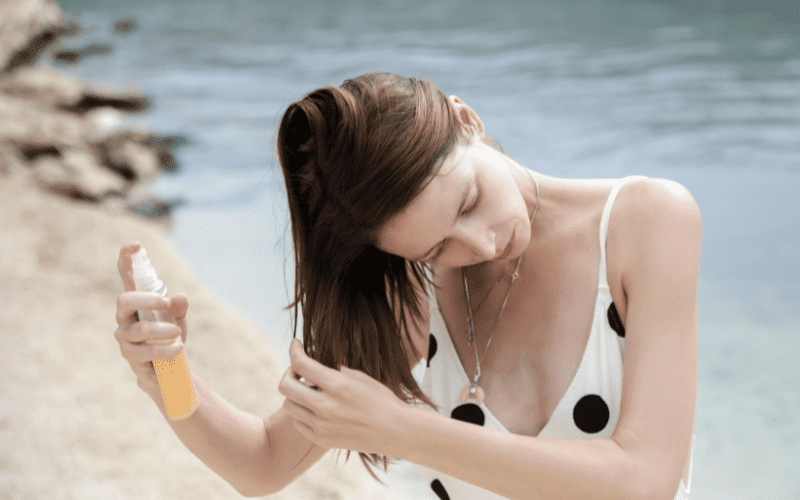 woman spraying her hair with a detangler