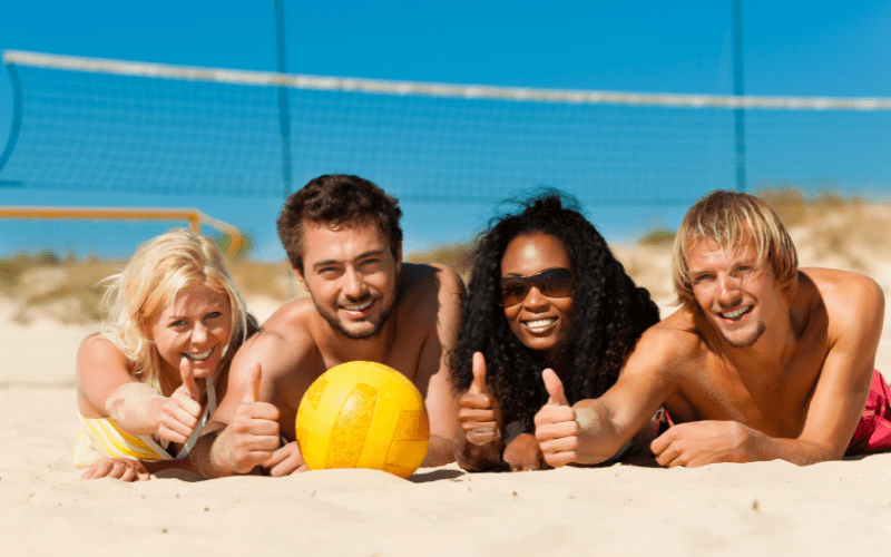 four people doing a "thumbs up" with a volleyball