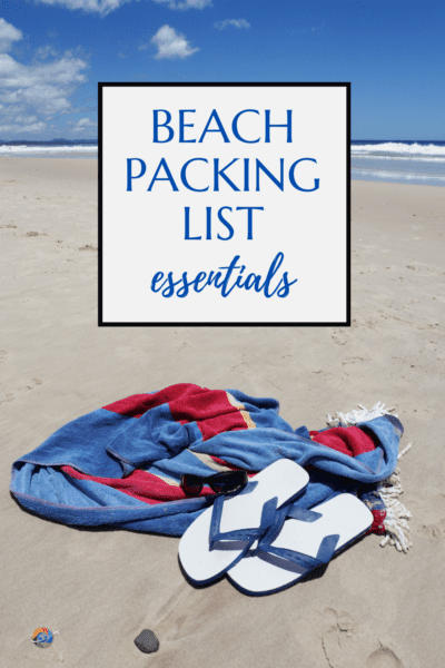 Red & blue towel and sandals on a beach. Text overlay says "beach packing list essentials."